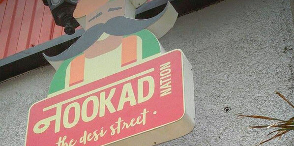 Die-cut blade sign carrying the Nookad Nation moustachioed mascot lockup.